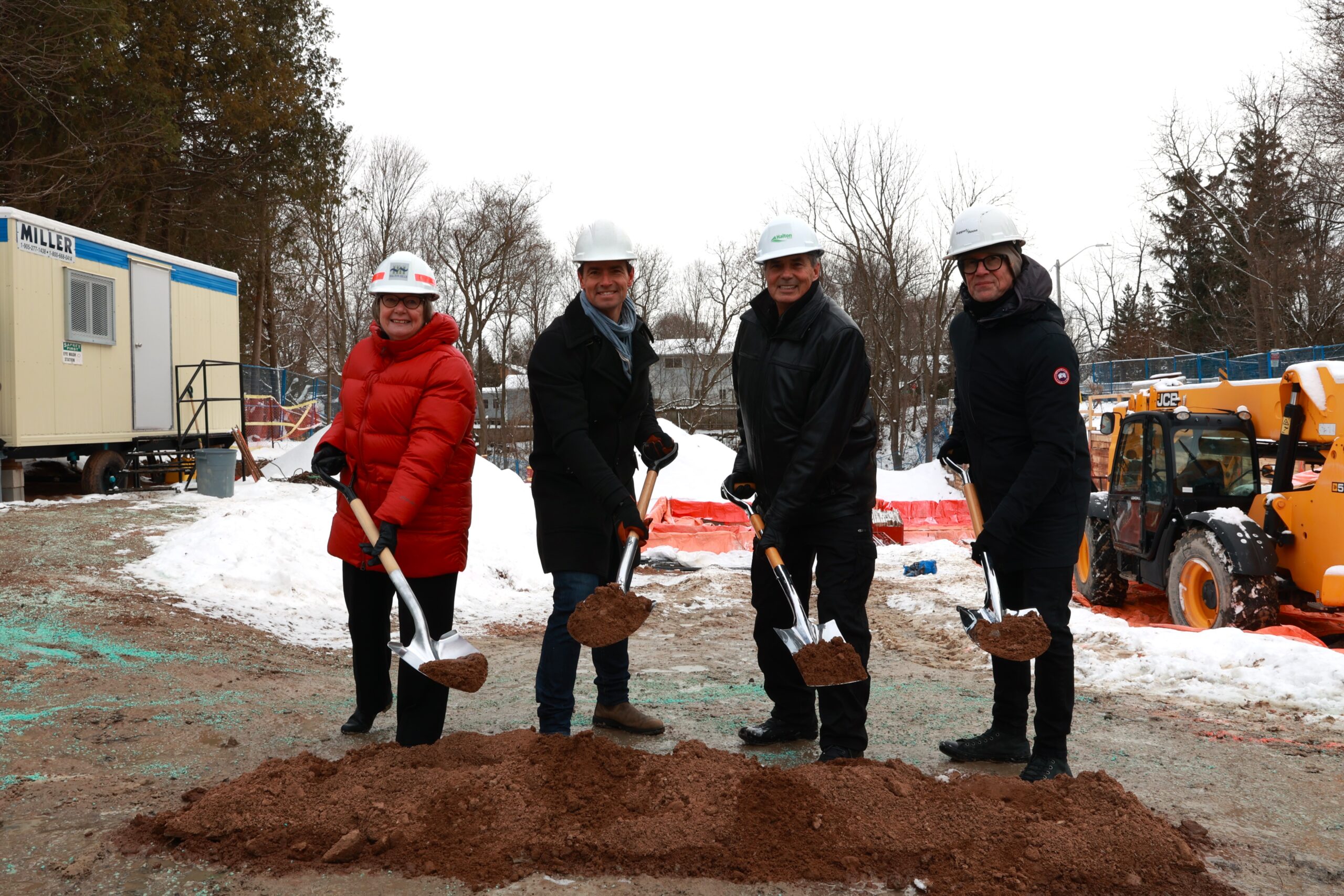 4 individuals with shovels full of dirt, smiling as they show the dirt to the camera